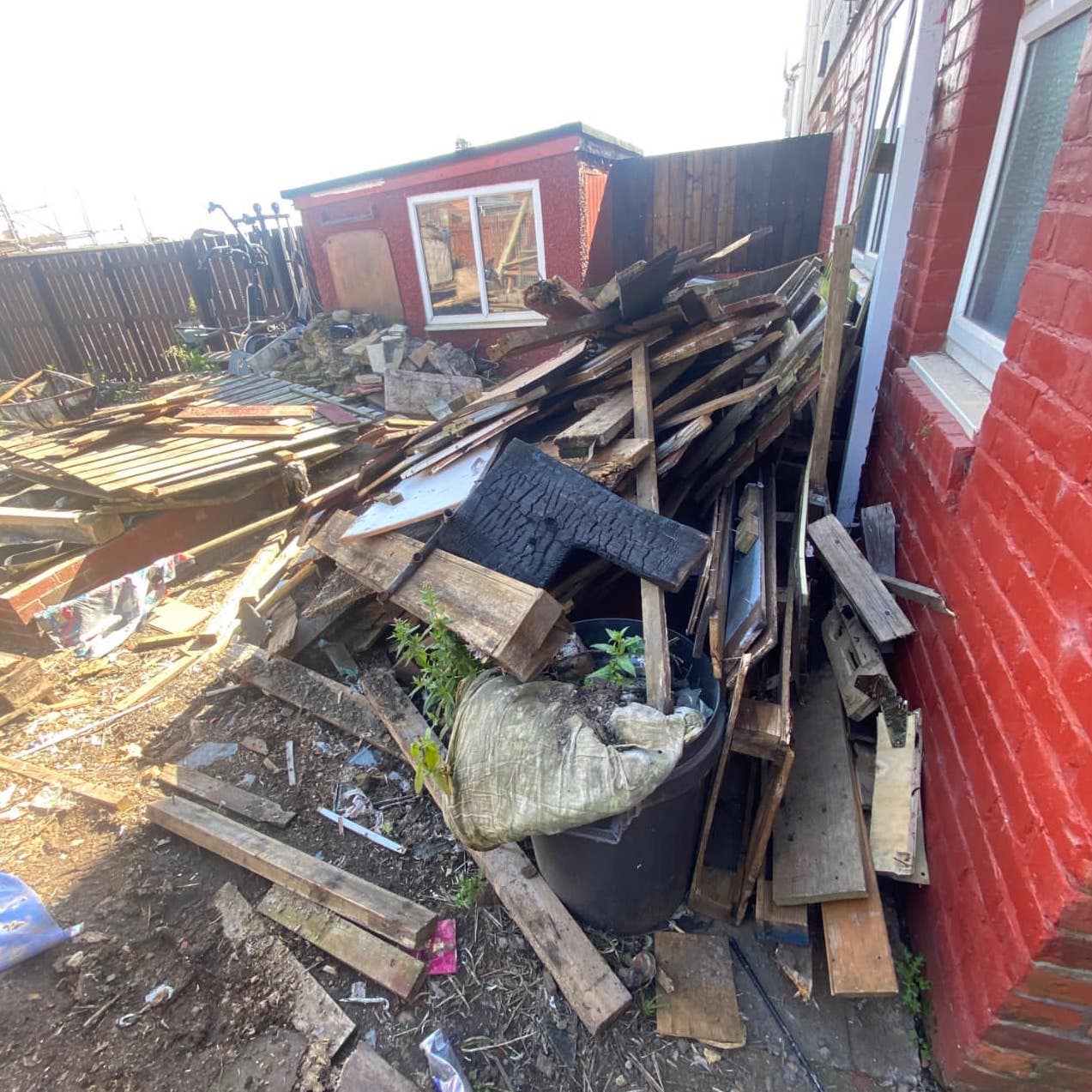 A filthy garden prior to landlord cleaning services from Invicta Environmental. There are large piles of rubbish.