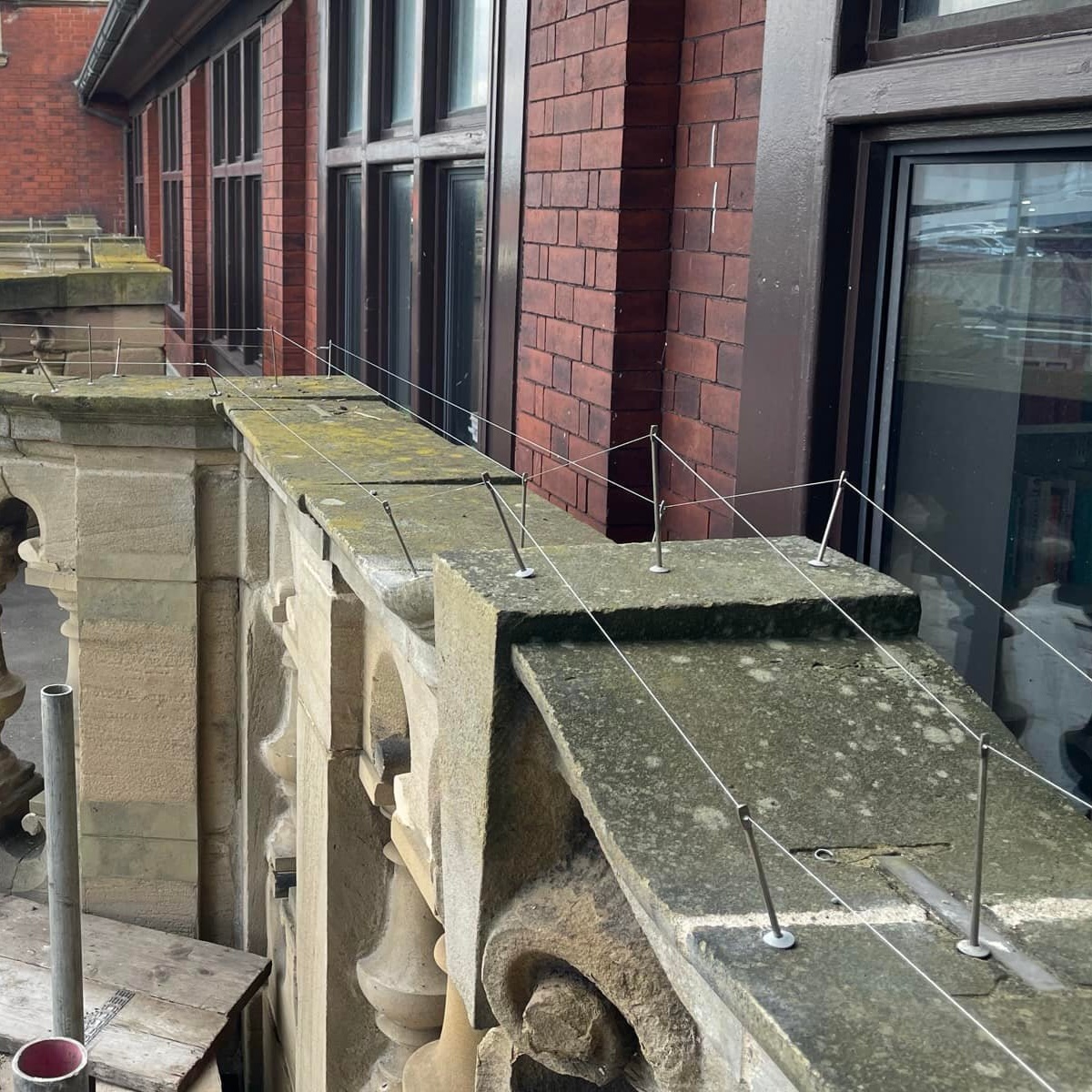 Bird post and wire system on a stone ledge on a building