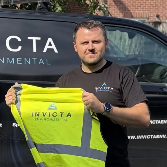 Pest Control Technician Callum holding uniform next to Invicta van